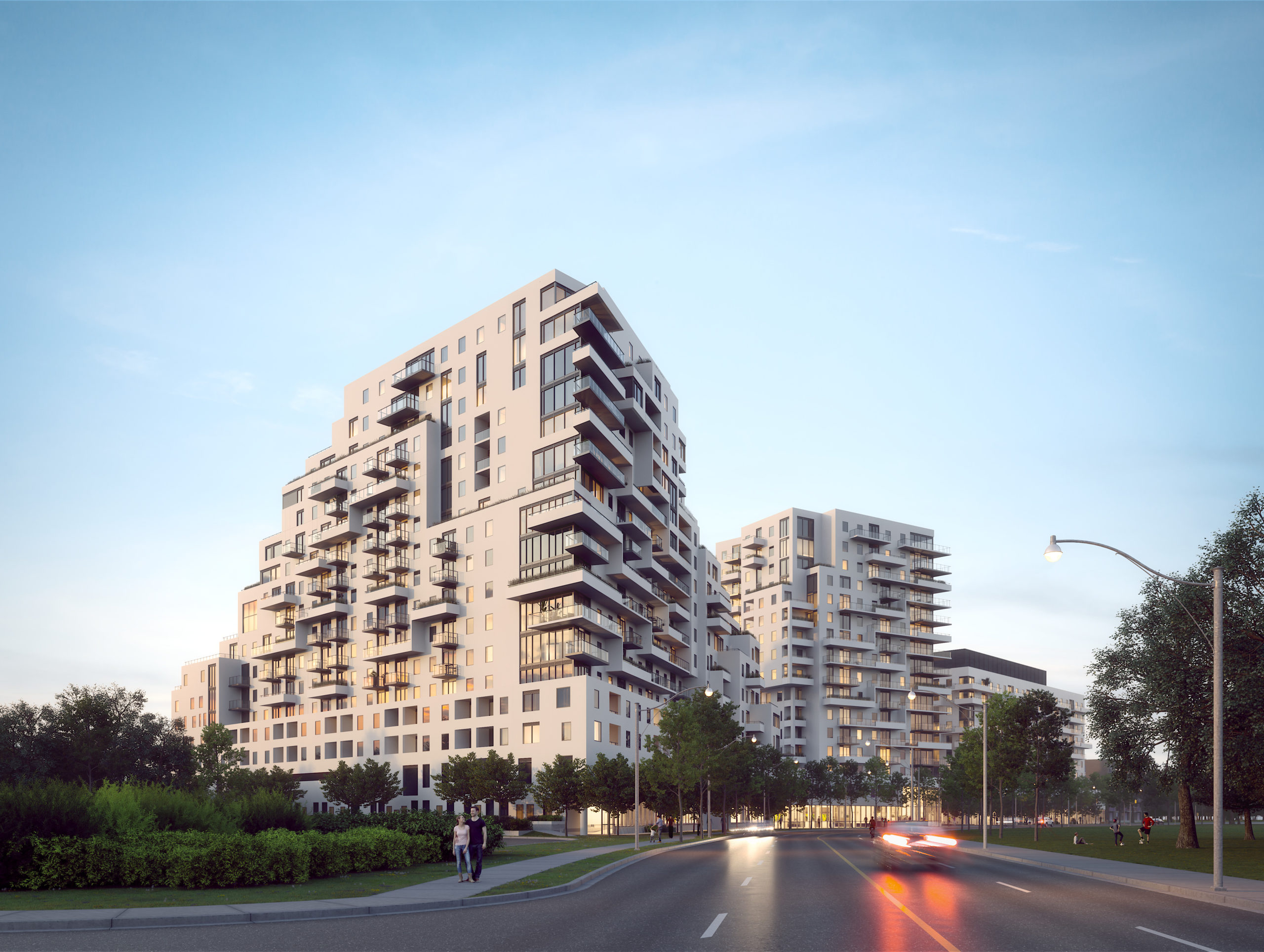 Evening street view of Queen & Ashbridge rental residences with green space in foreground.